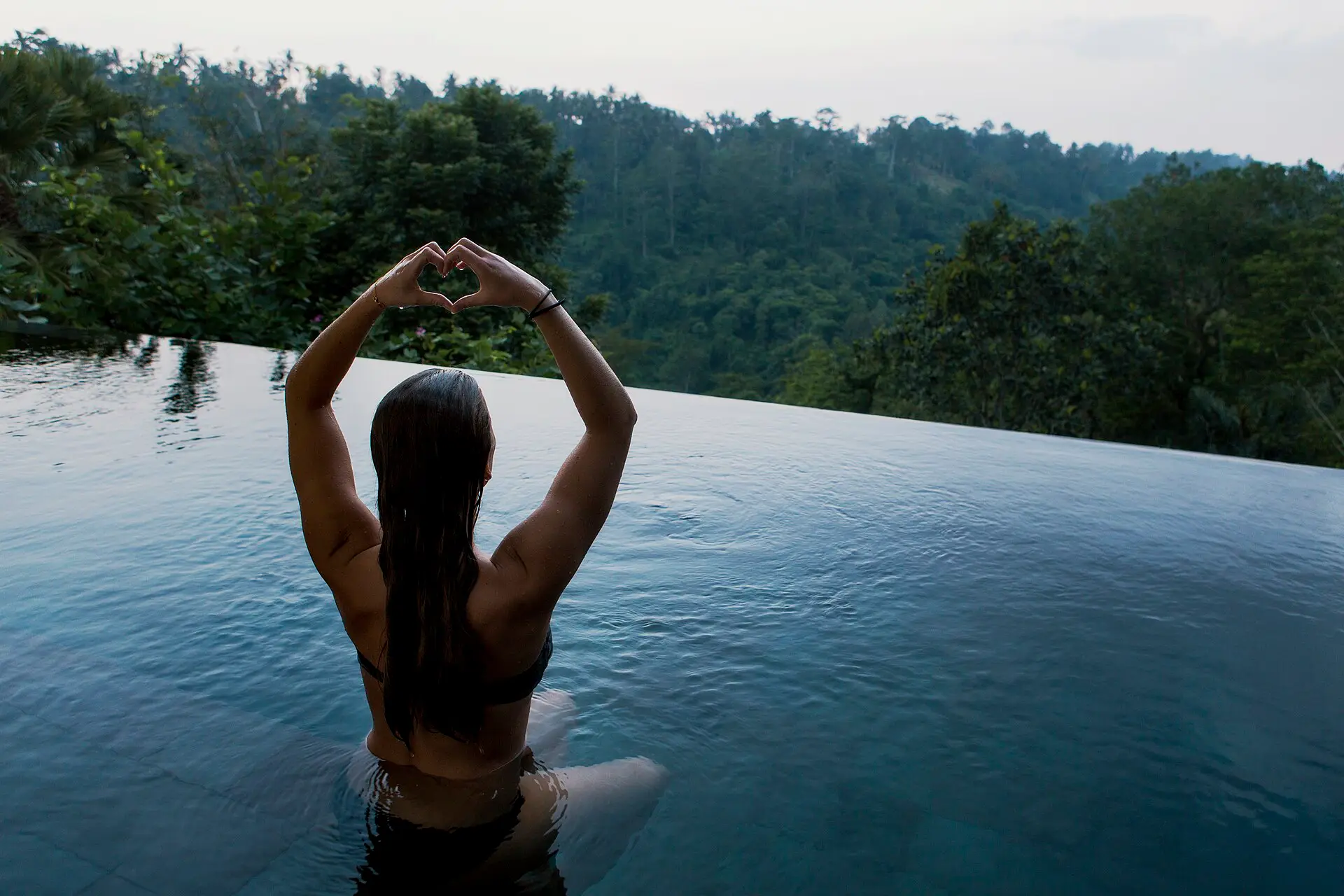 A guest meditating in an infinity pool above the forest