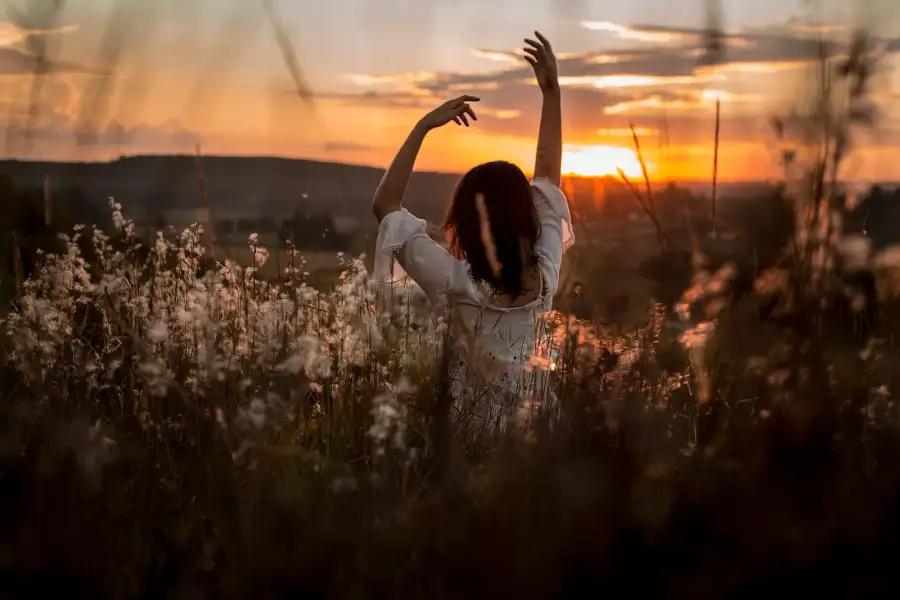 A woman stretching in a meadow at sunrise